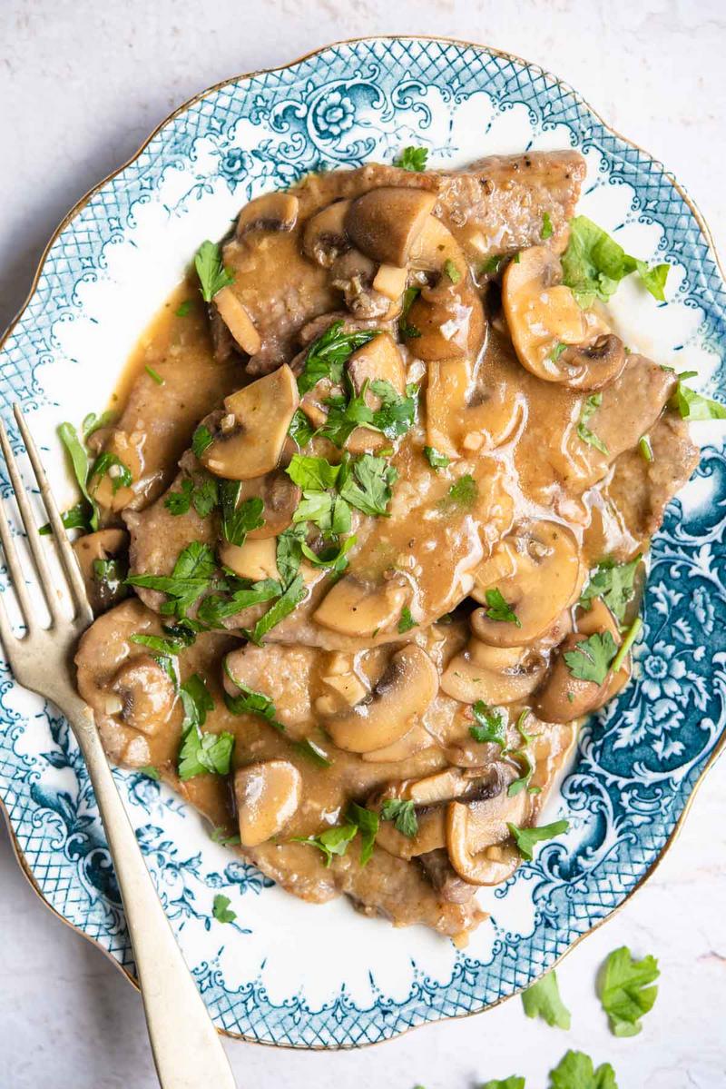 Veal in a Marsala cream sauce with mushrooms, served on a patterned plate